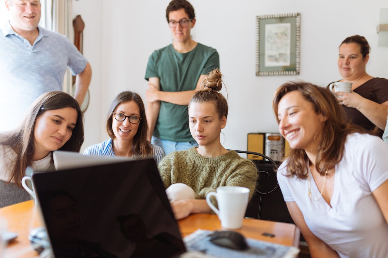 about-01 A diverse group of adults at work, enjoying a casual meeting indoors with focus and smiles.
